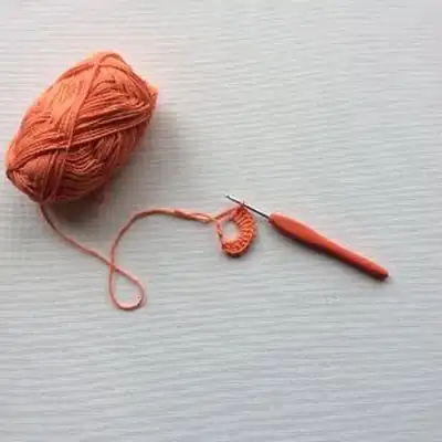 Orange granny square bottle holder in progress with bottle