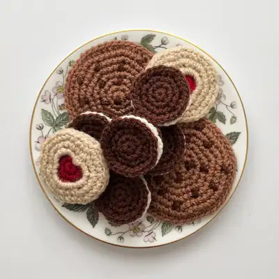 stack of crocheted biscuit amigurumi on a plate showing Choc Chip and Oreo styles
