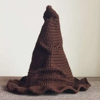 Finished brown Sorting Hat crochet hat with pointed crown and ruffled brim, displayed on a neutral surface