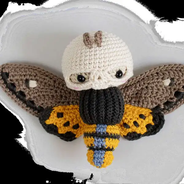 Close-up of the moth head showing skull mask fitted over the head and the eye placement for the amigurumi