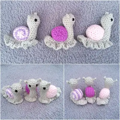 Three small Garden Snails with contrasting shells on a soft grey surface, finished amigurumi shells and frilled bases visible