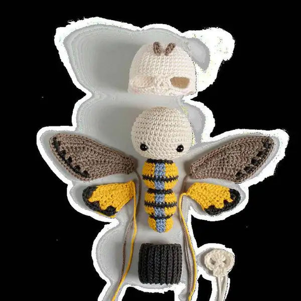 Two small yellow and black inner wing pieces completed, photographed side by side as right and left wings for the amigurumi