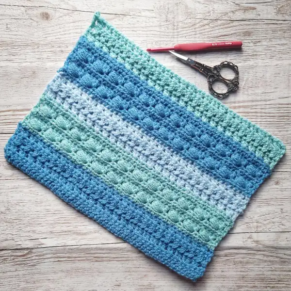 Close-up of Sideways Puff Stitch clusters in progress on the cushion panel showing long loops and hook