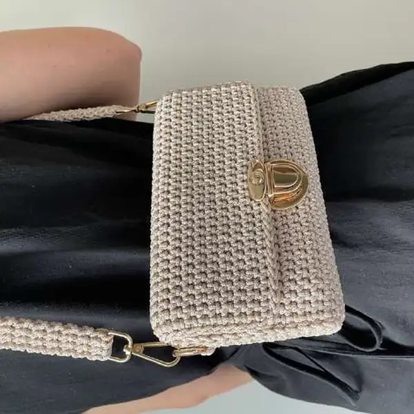 Finished strap and D-ring attachment on the side of the beige crochet mini crossbody bag