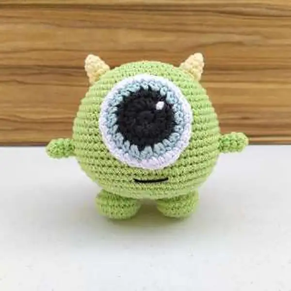 Back view of small green Mike Wazowski amigurumi showing horn placement and round body