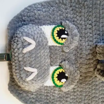 Gray plush dinosaur backpack with orange wings, front view