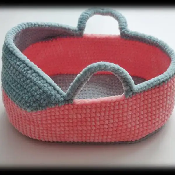 Top-down view showing the light blue base and pink walls of the crochet cradle amigurumi with neat back-loop edge
