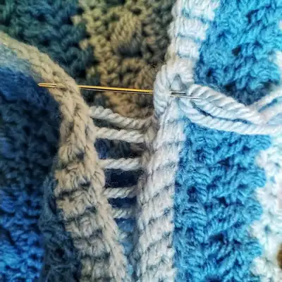 Finished Snowberry cushion cover in blue and teal stripes showing textured Sideways Puff Stitch amigurumi-style surface