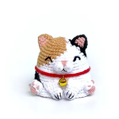 Front view of finished calico cat amigurumi with tan patch and red collar