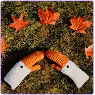 Goose mittens orange and white on grass, close-up