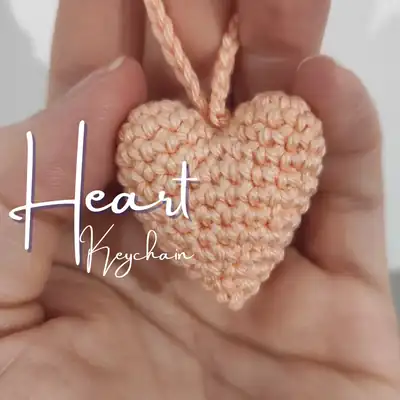 peach crocheted heart keychain held in hand showing front of finished amigurumi heart