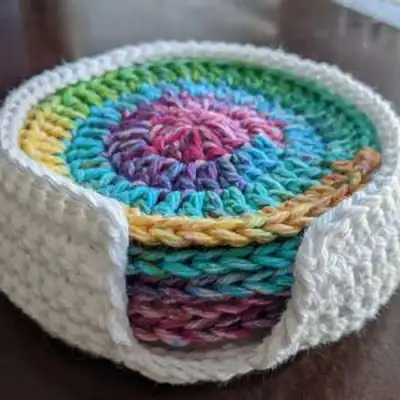 Rainbow-colored circular coaster in progress on a wooden surface