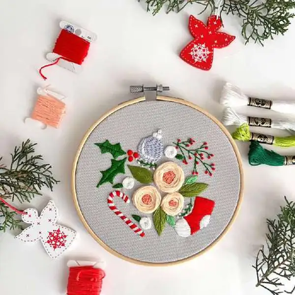 Flatlay of finished hoop with DMC strands and embroidery needle, illustrating materials used