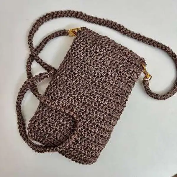 Pocket detail and strap attachment close-up on brown crochet bag