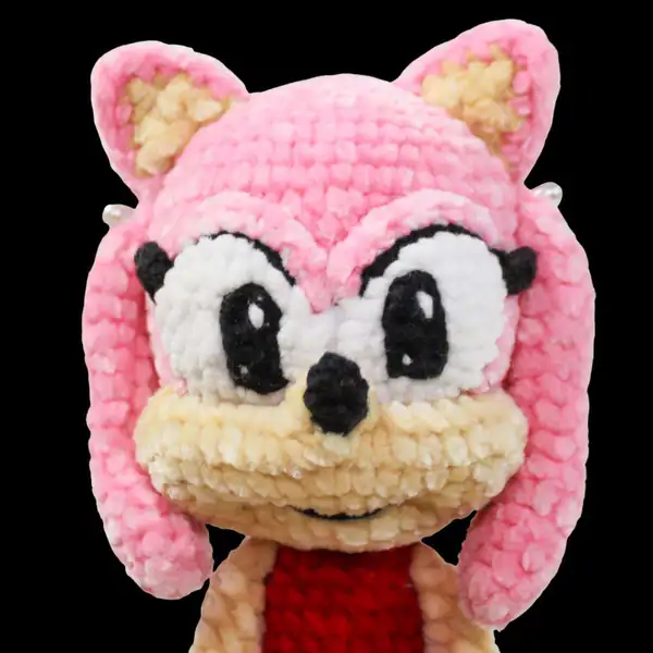 Sewing pink Rascal together with a crochet hook