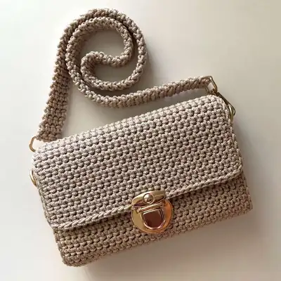 Beige mini crossbody bag amigurumi style? No amigurumi; image shows finished bag with strap coiled and brass clasp visible