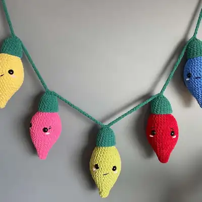 A colourful string of Festive Lights crochet bulbs in multiple colours forming an amigurumi garland